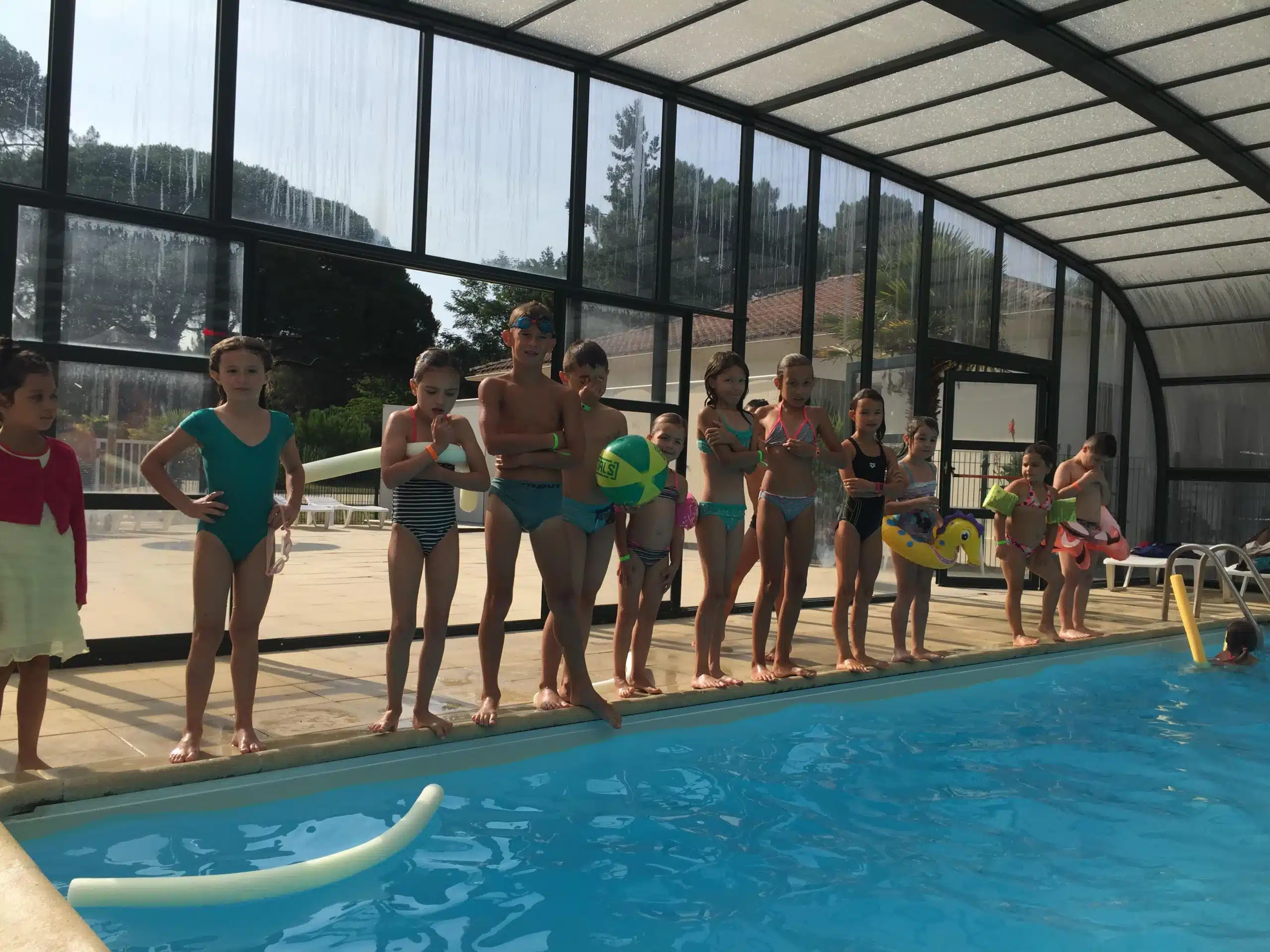 Kinder im Hallenbad, die auf das Schwimmen warten.