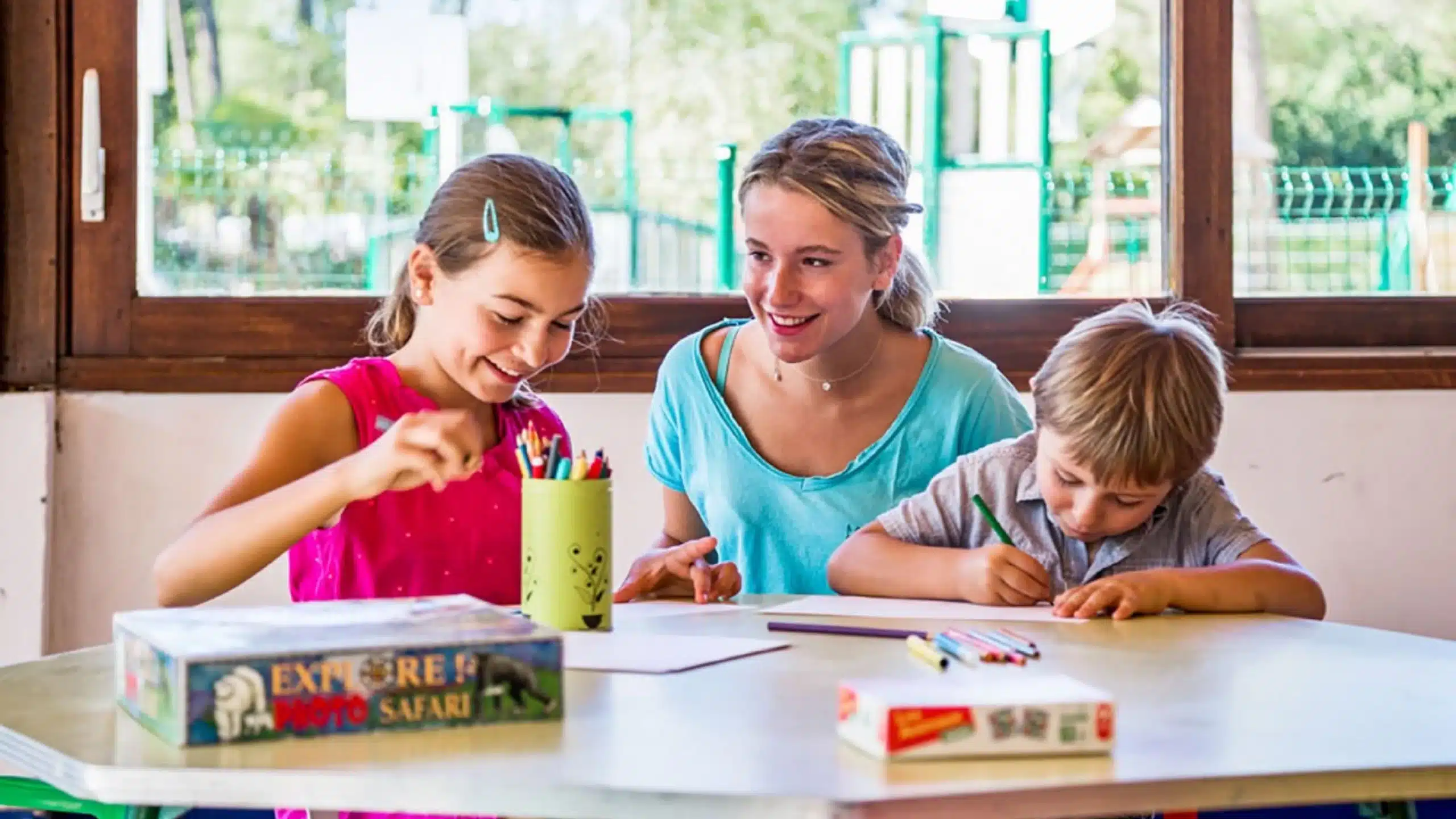 Enfants et animatrice dessinent ensemble à une table.