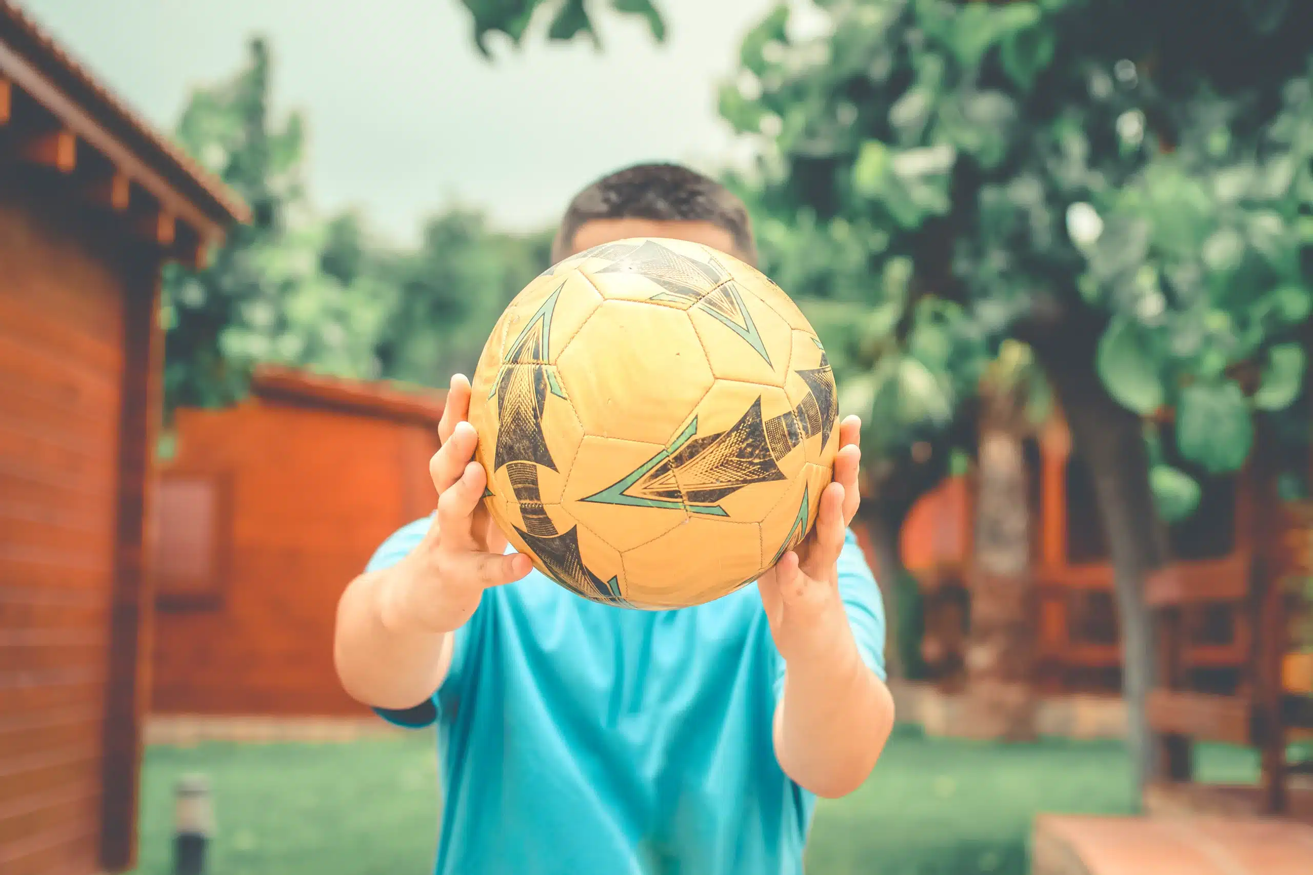 Personne tenant un ballon de football jaune.