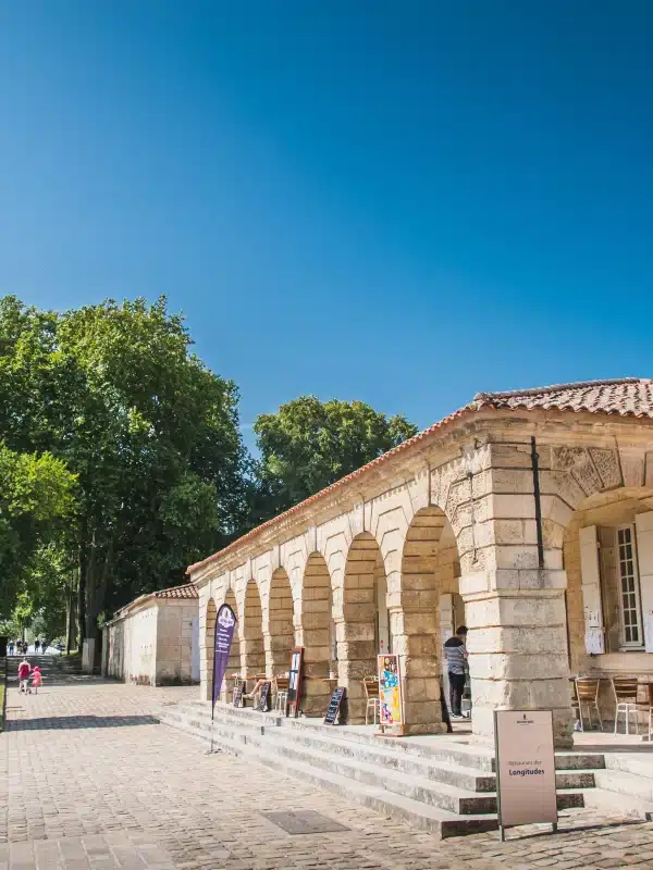 Monument historique en pierre, chemin en pavés, arbres verts.