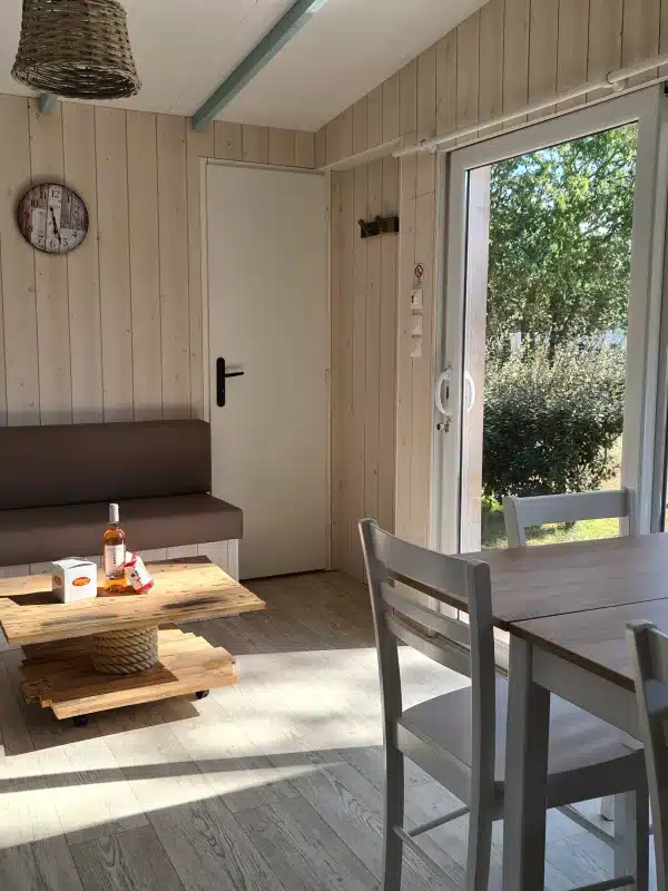 Salon lumineux avec table, chaises et extérieur.