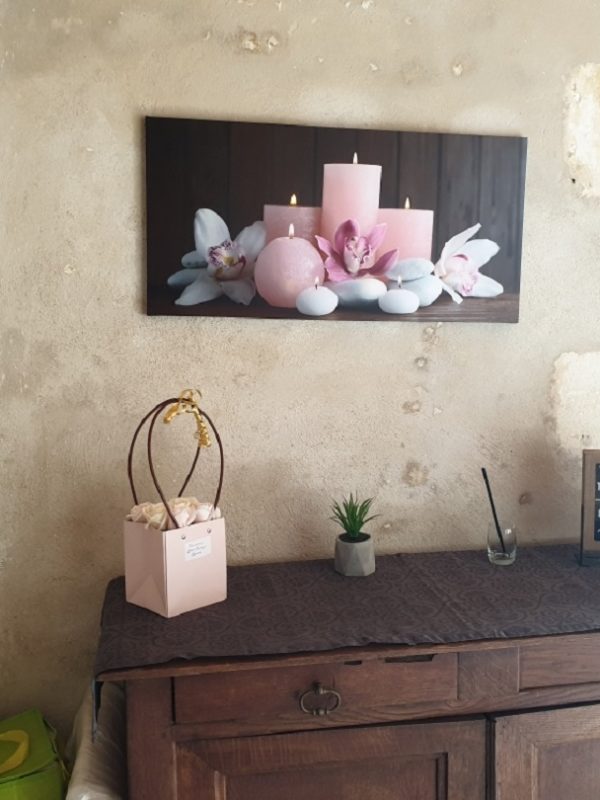 Intérieur avec tableau bougies et plantes sur un meuble.