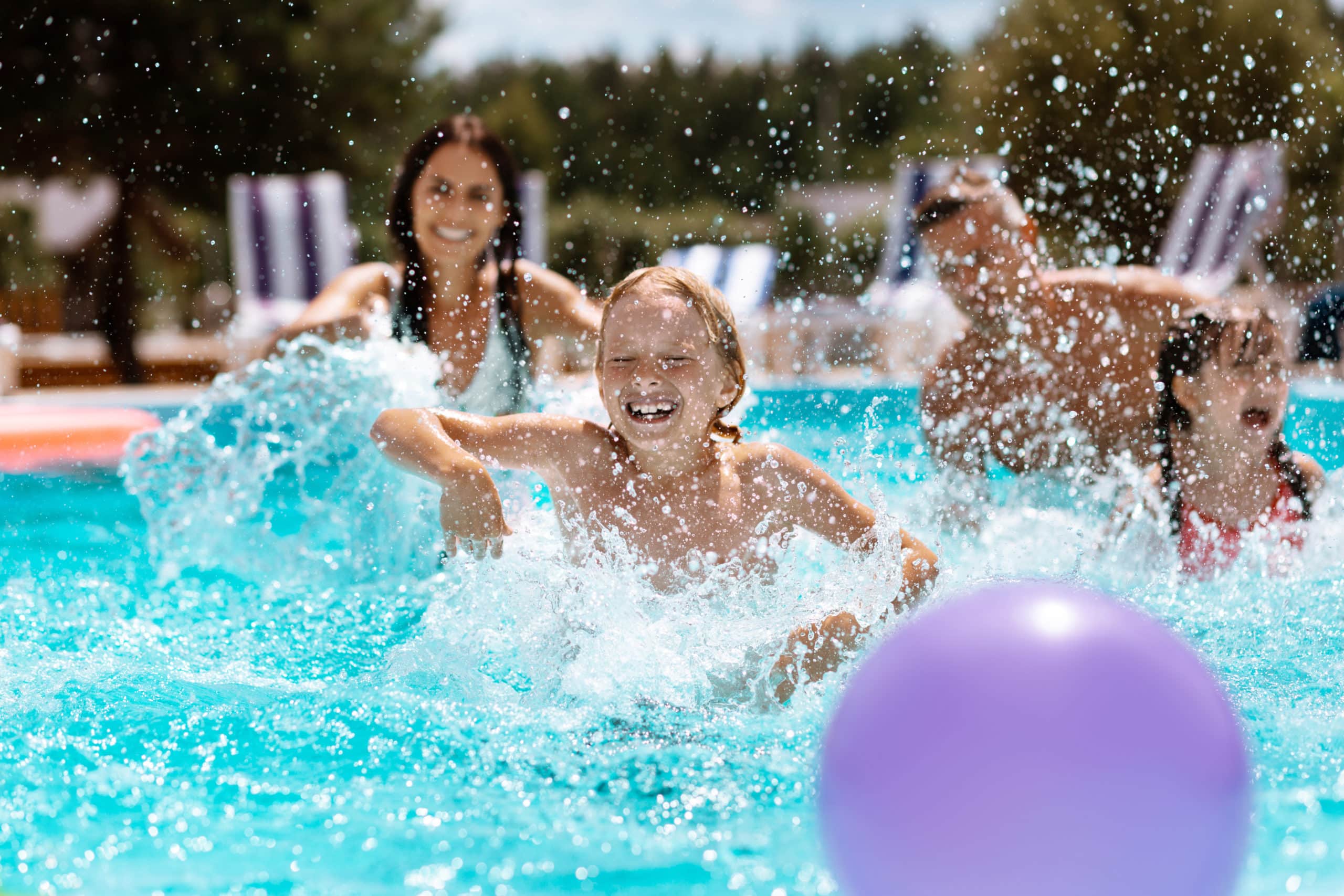 Enfants jouant dans une piscine avec ballon violet.