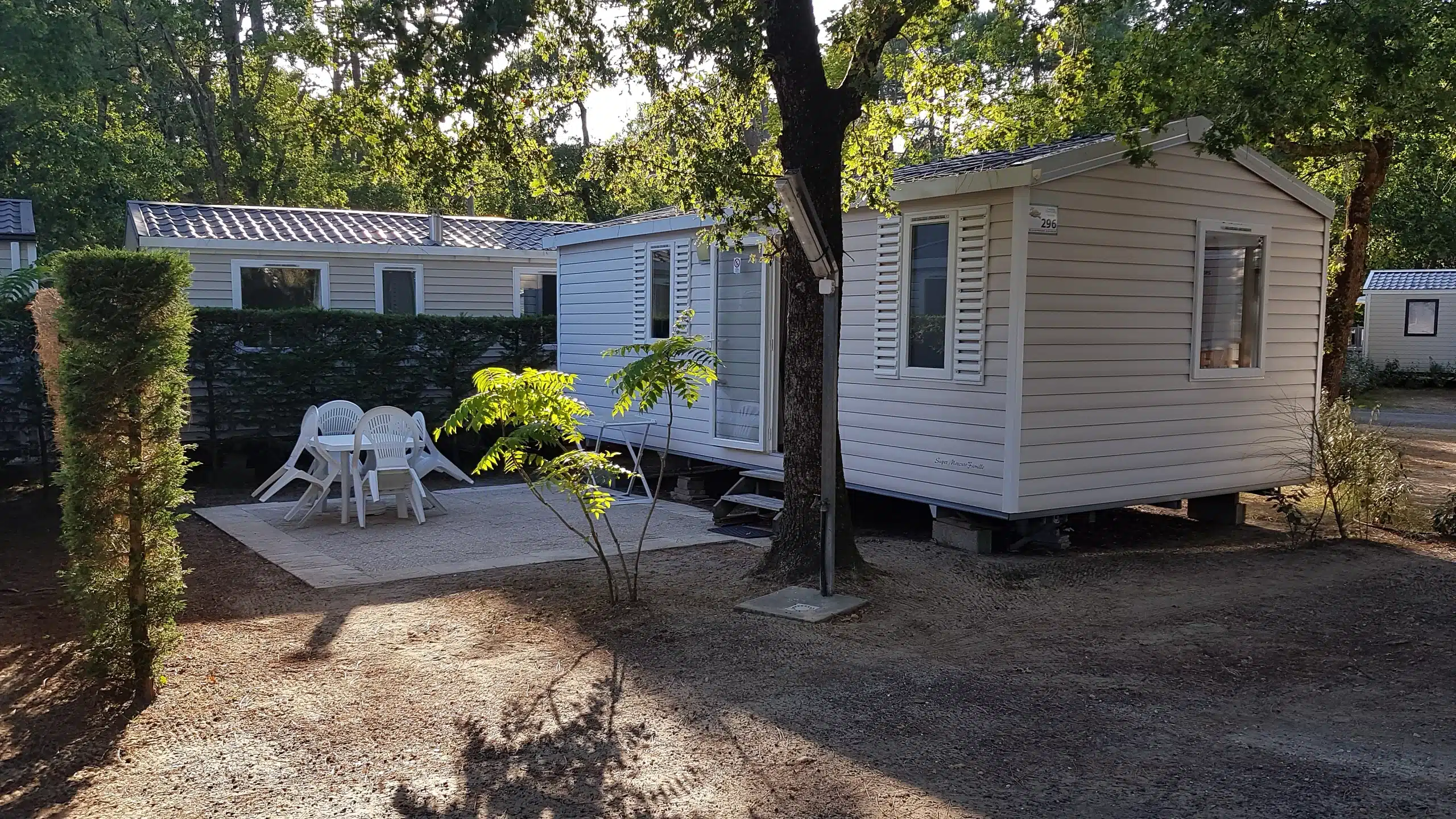Mobil-home avec terrasse dans un camping ombragé.