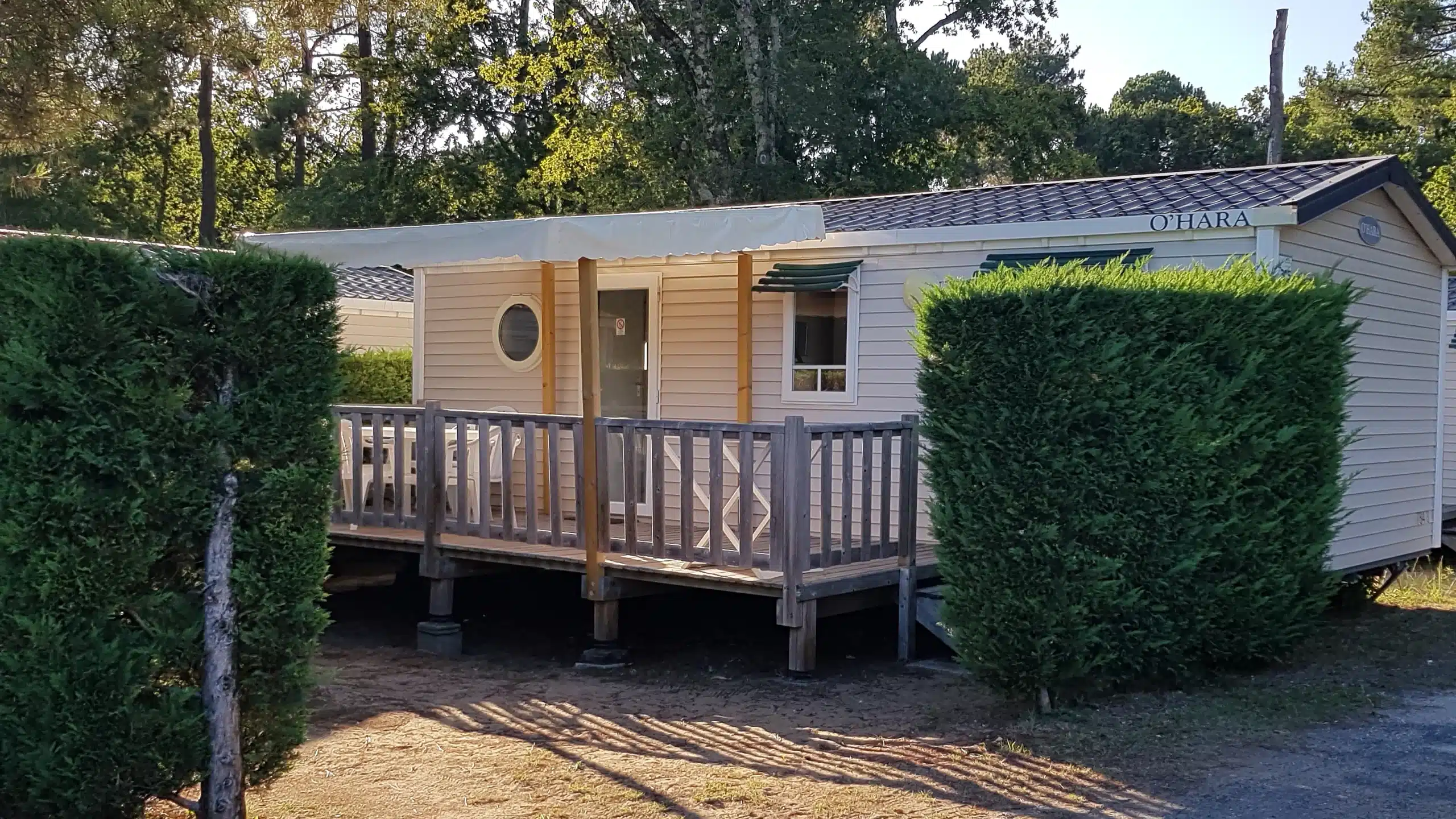 Mobil-home avec terrasse devant des arbres