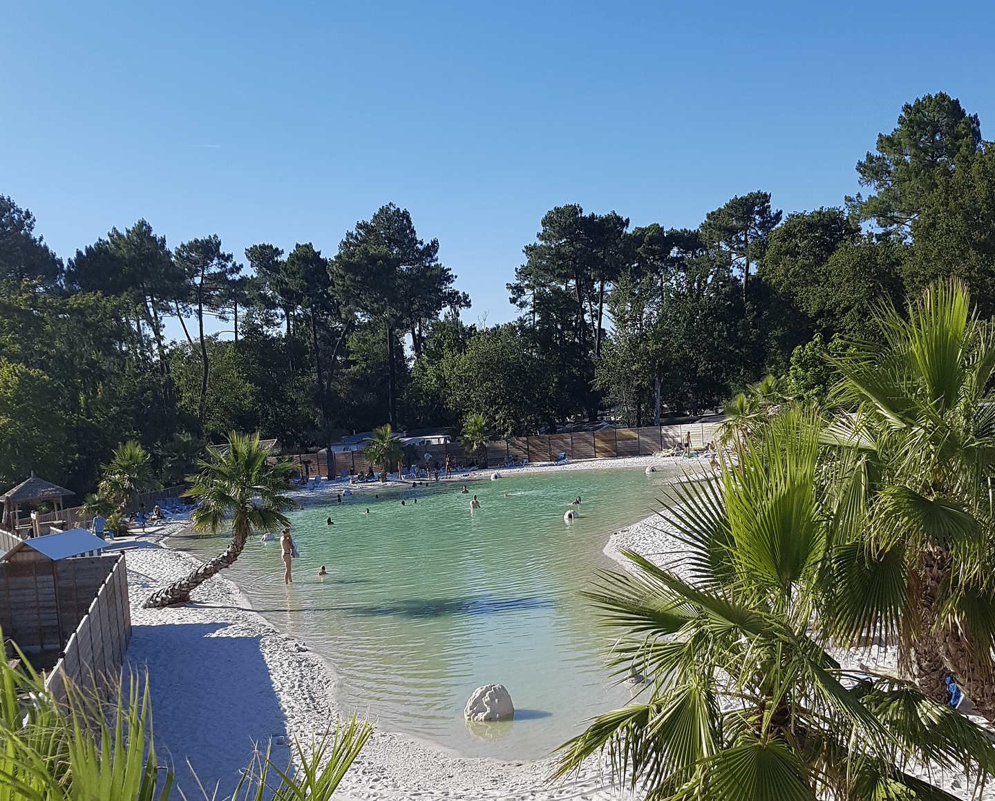 Plage artificielle avec palmiers et eau turquoise.