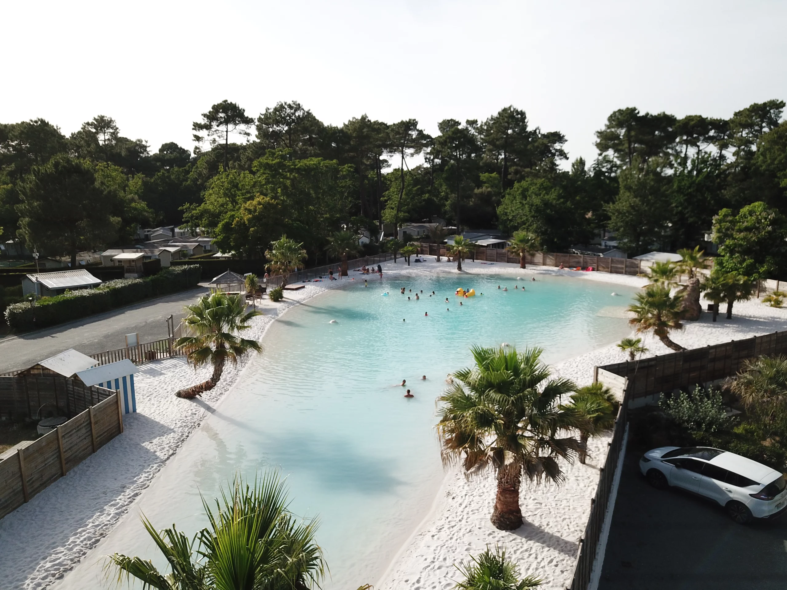 Plage artificielle avec palmiers et baigneurs.
