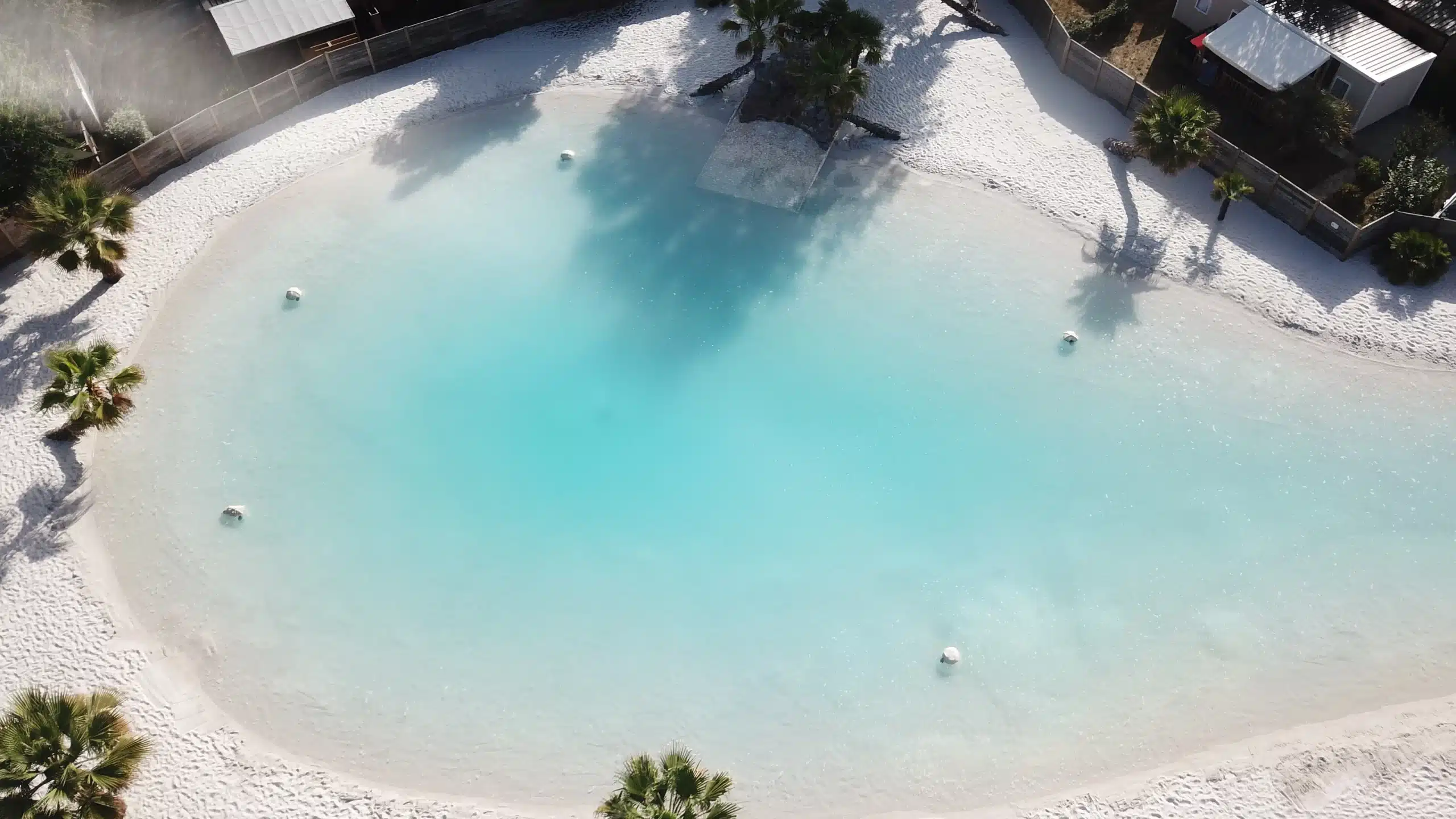 Vue aérienne d'une piscine lagon avec plage de sable.