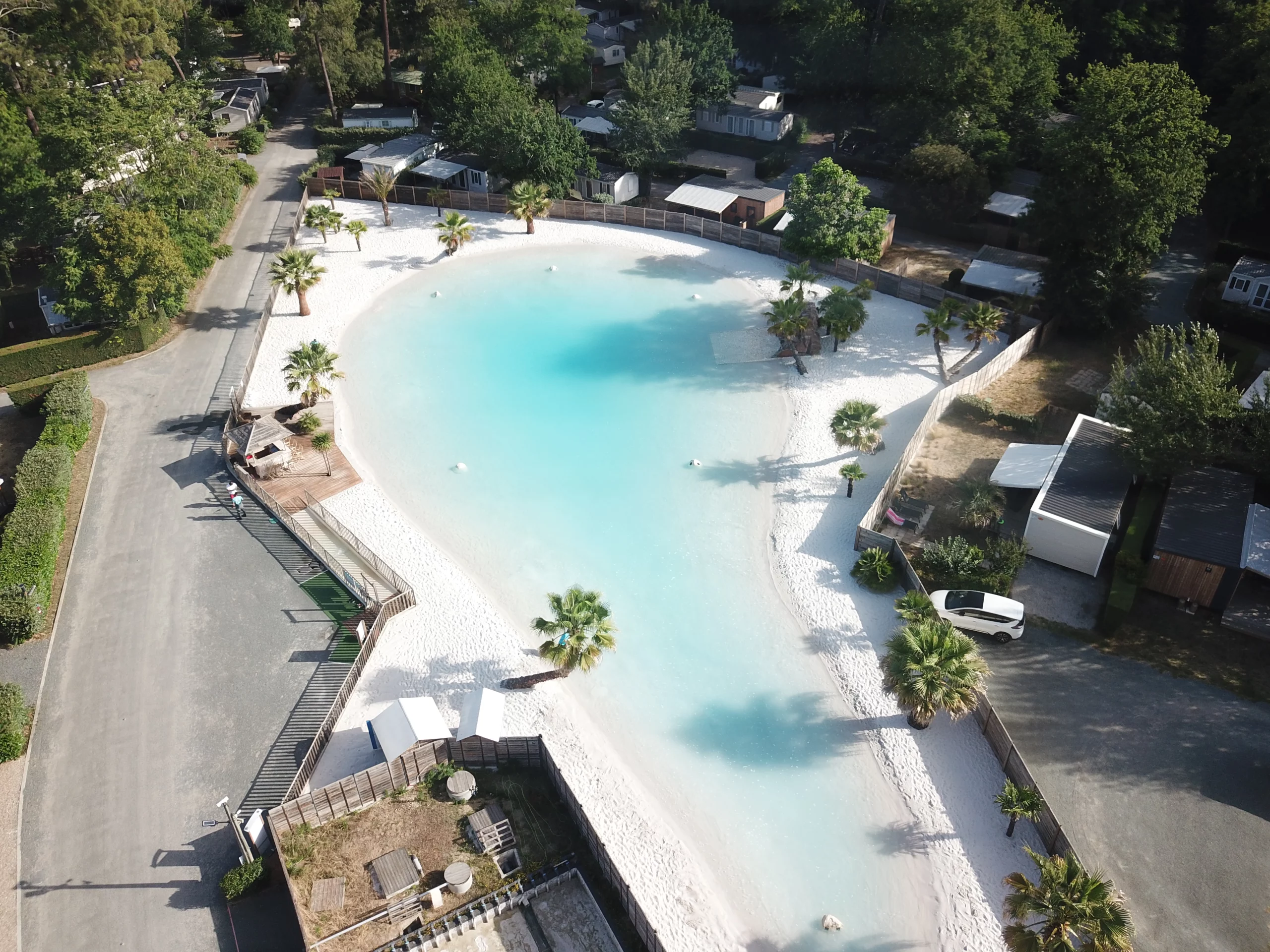 Plage artificielle avec eau turquoise et palmiers.