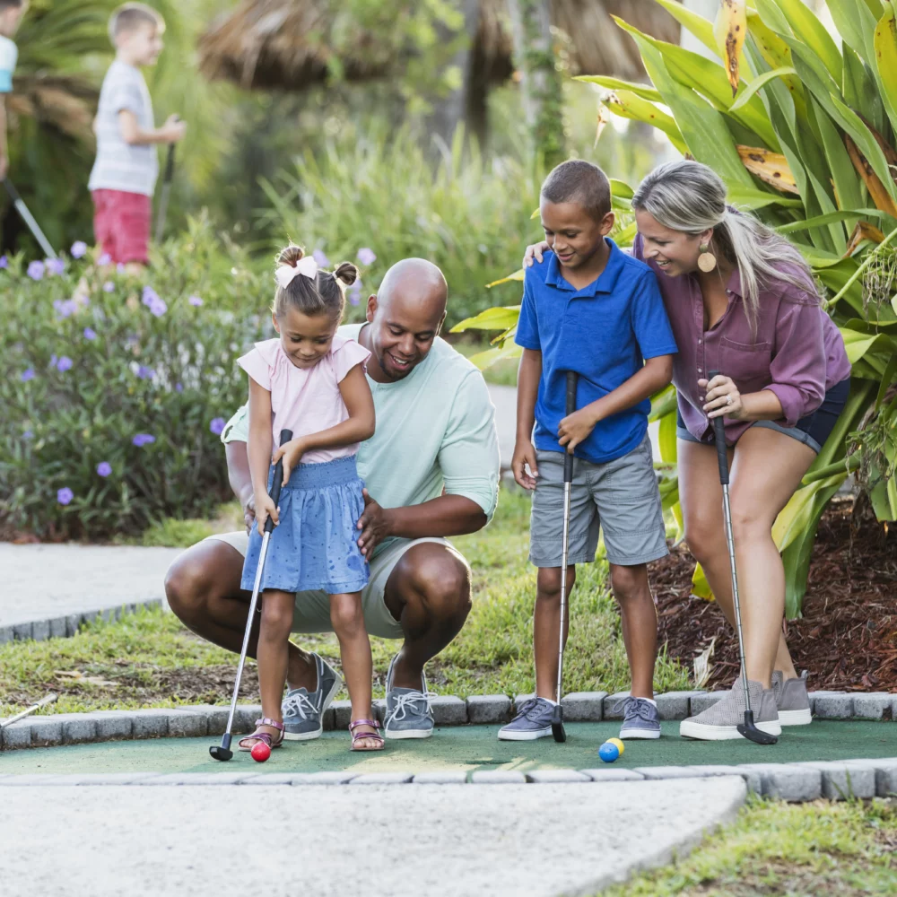 Famille jouant au mini-golf ensemble joyeusement.