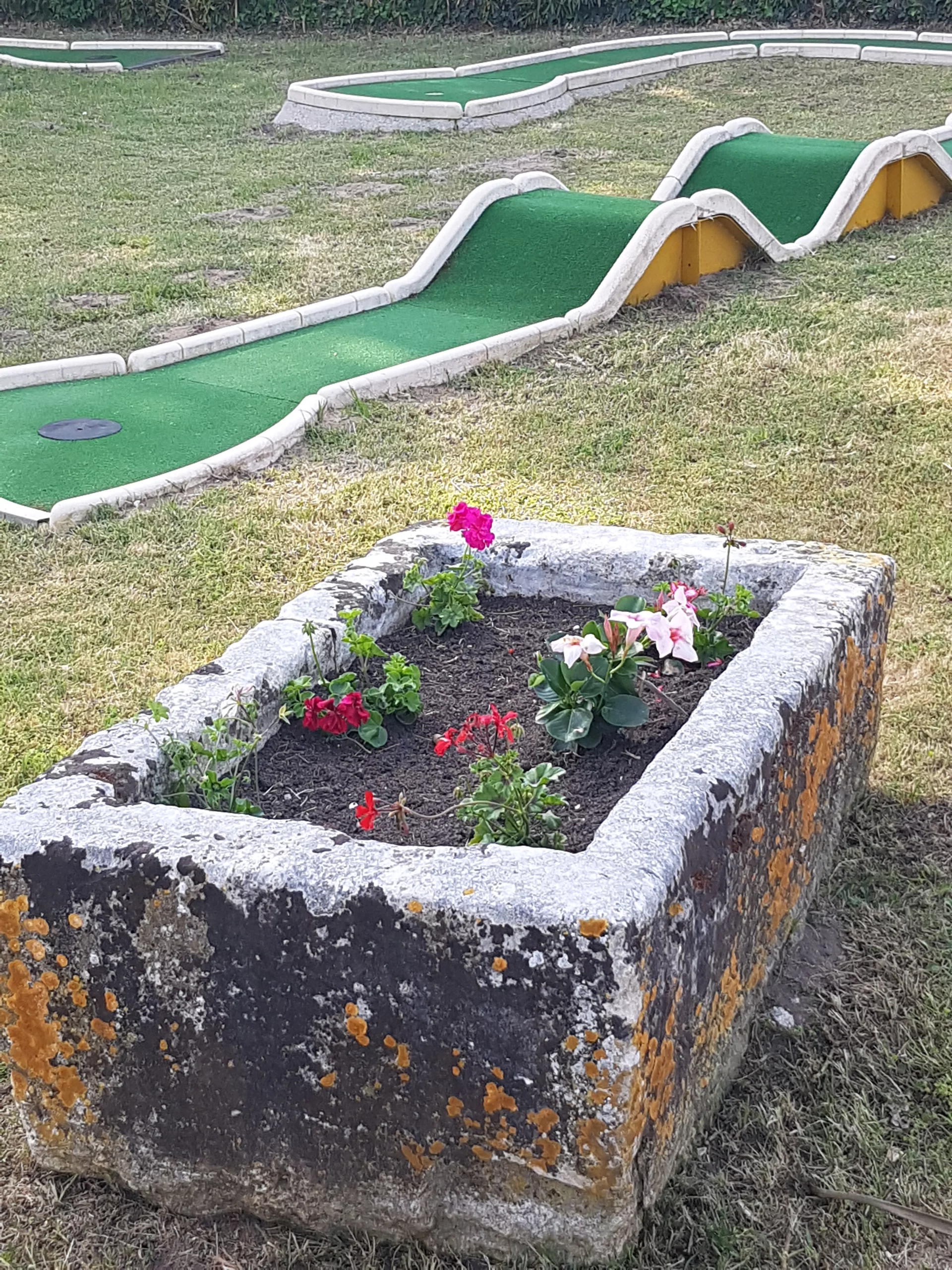 Parcours de mini-golf avec jardinière en pierre.