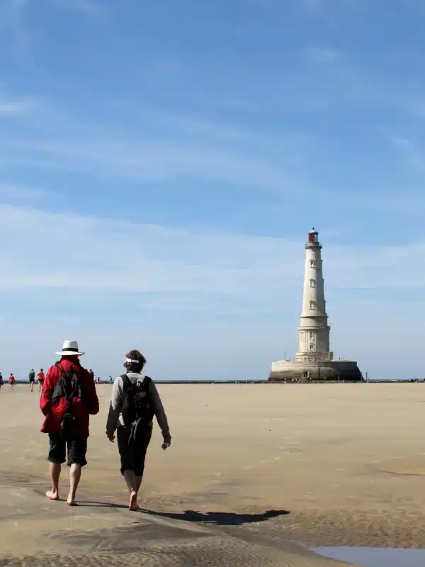 Promeneurs sur une plage près d'un phare.