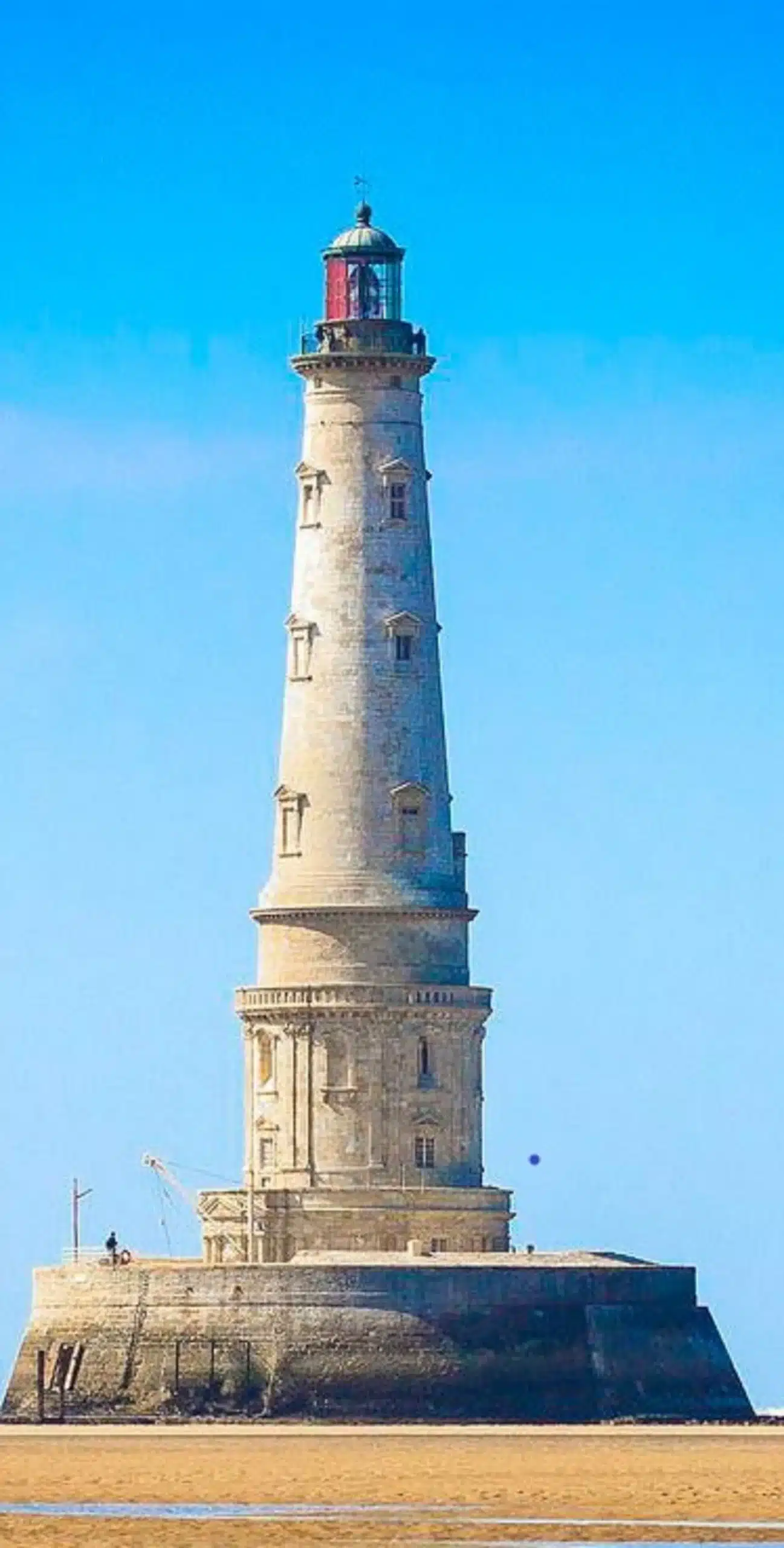 Phare surplombant le sable avec ciel bleu