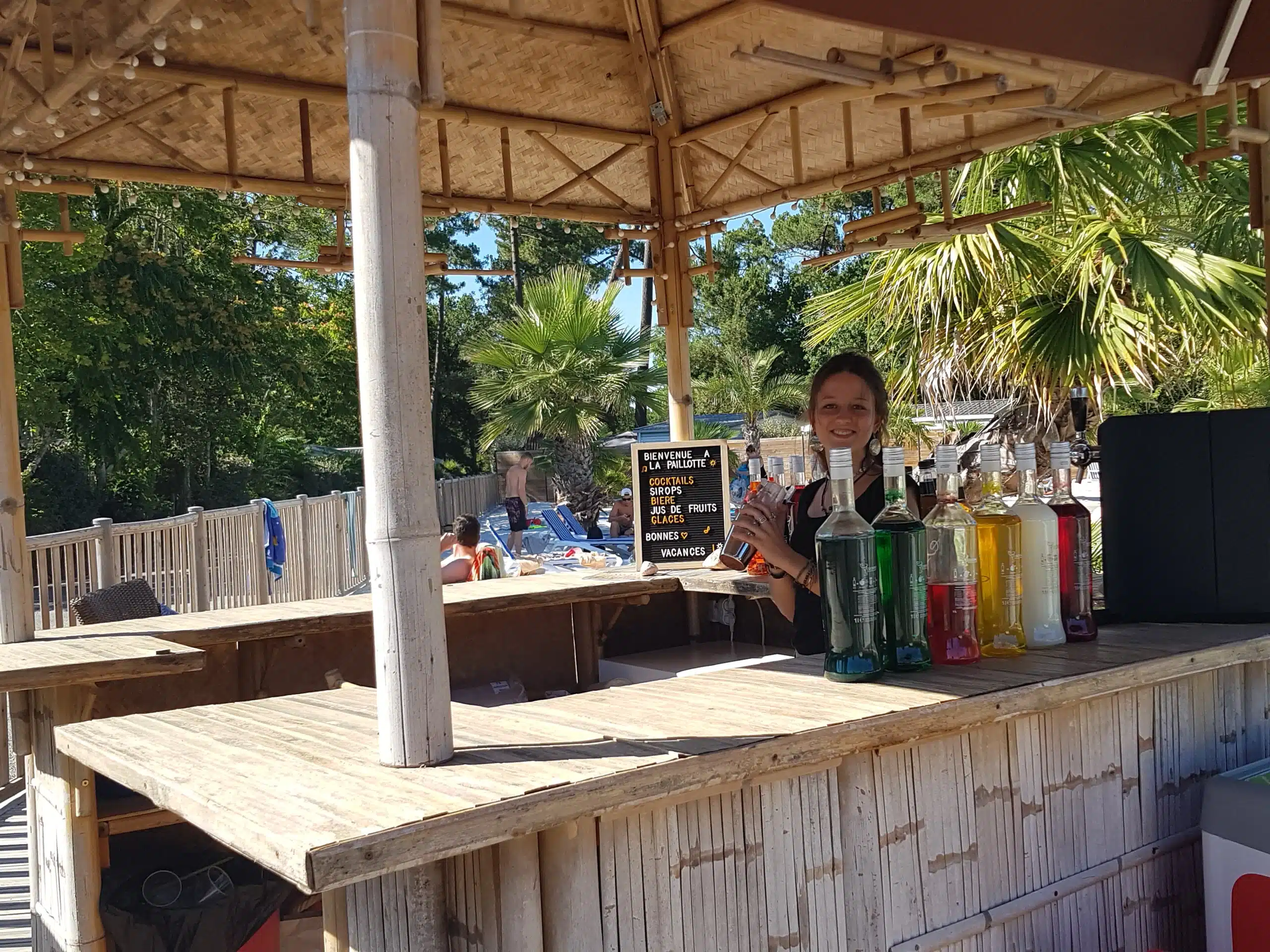 Bar tiki en plein air avec bartender souriant.