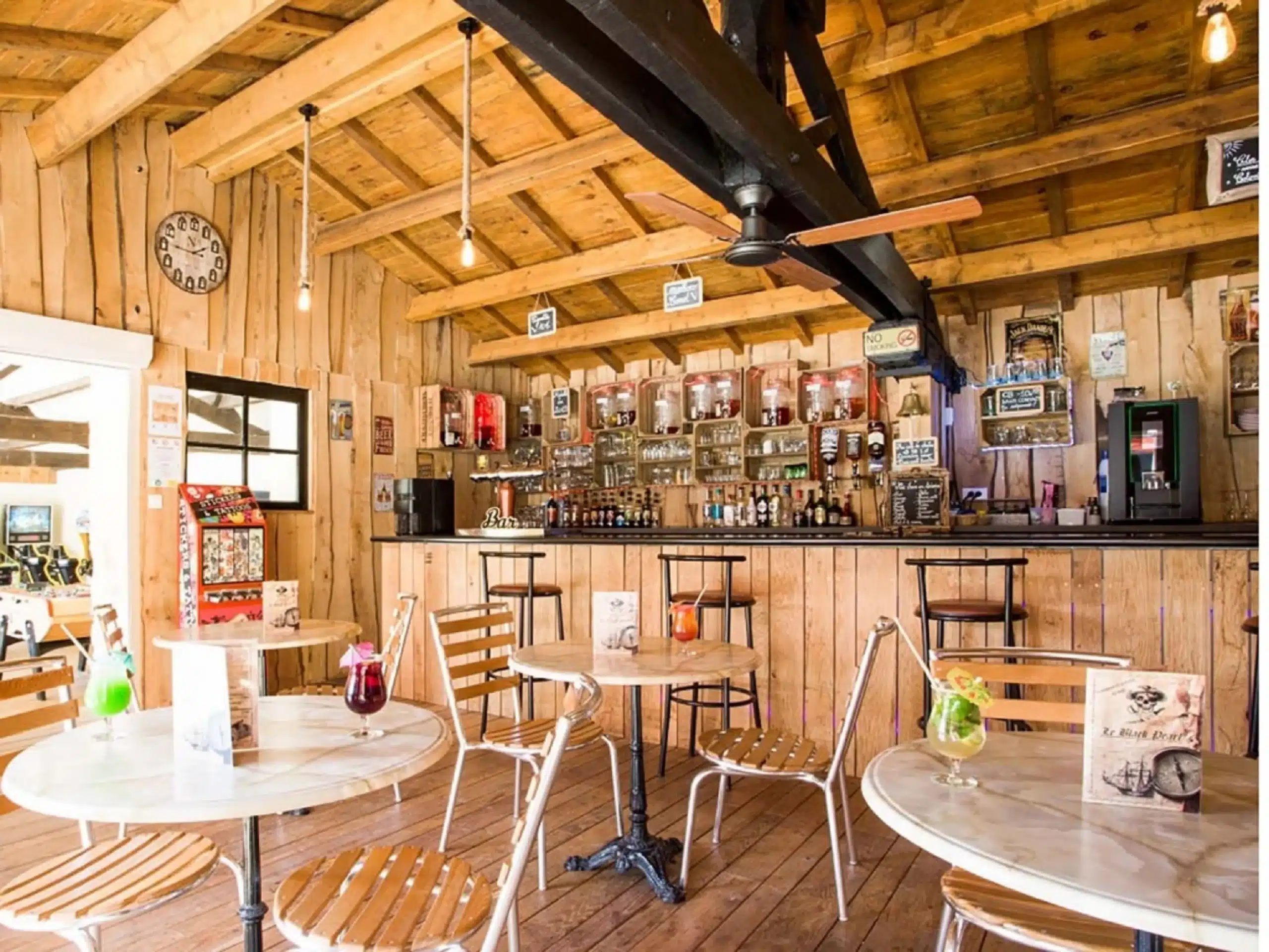 Intérieur de café en bois, tables et boissons colorées.