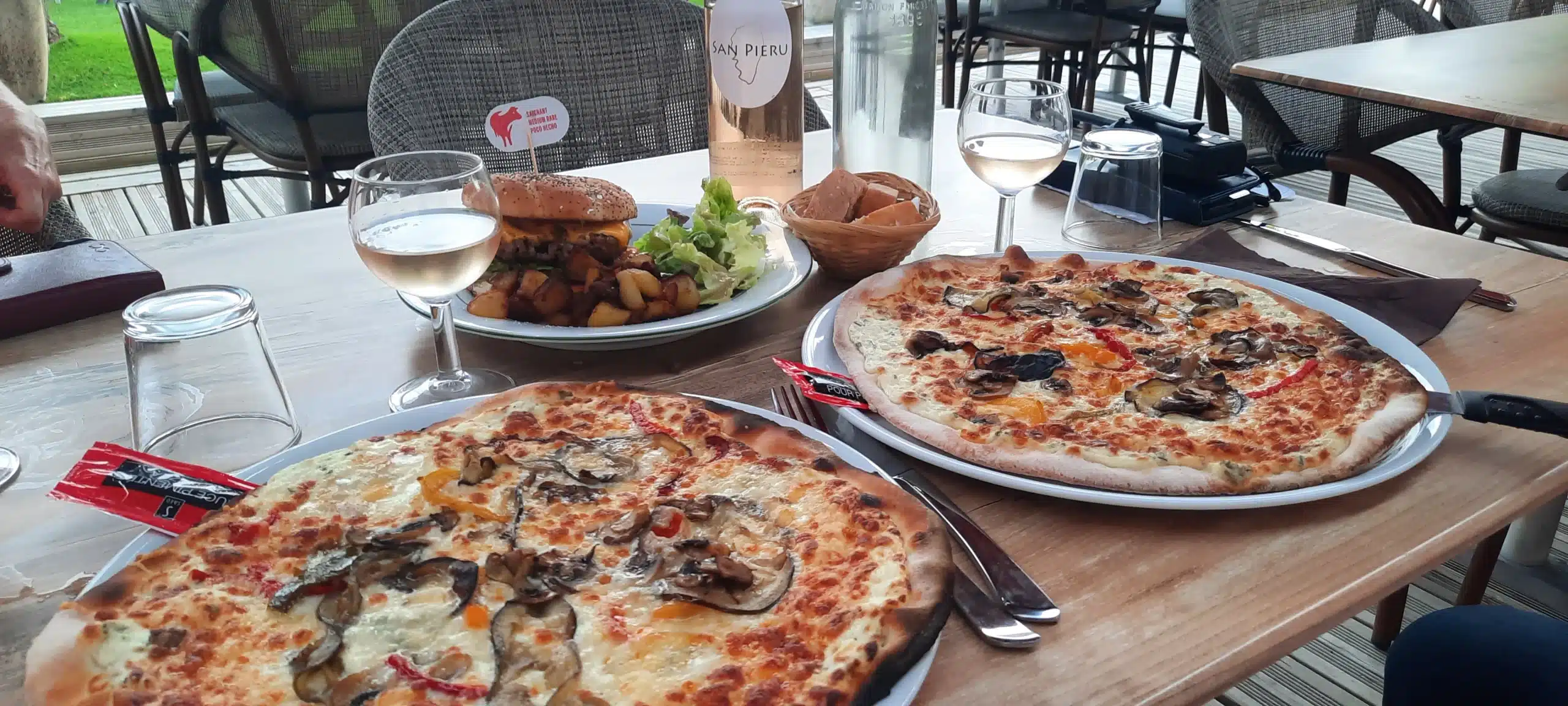 Deux pizzas et un hamburger sur la table.