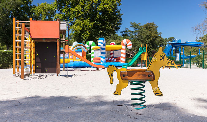 Aire de jeux pour enfants avec cheval à bascule et châteaux gonflables dans le sable