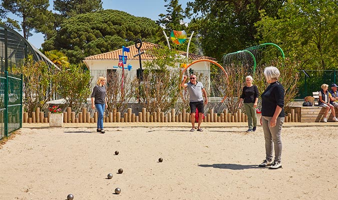 Groupe d'mais jouant à la pétanque sur le terrain de pétanque du camping